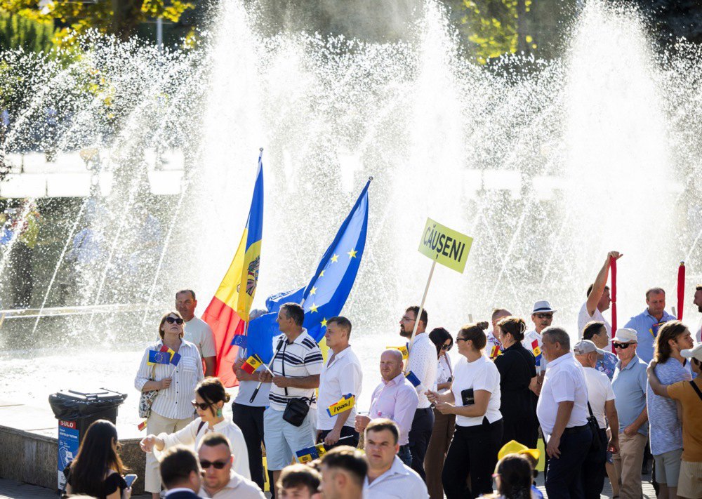 Люди з прапорами Молдови та ЄС під час передвиборчої кампанії партії PAS перед будівлею Національної опери в Кишиневі, 29 серпня 2025 року